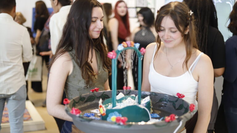Dos alumnas observando su obra en una exposici&oacute;n de cer&aacute;mica modernista
