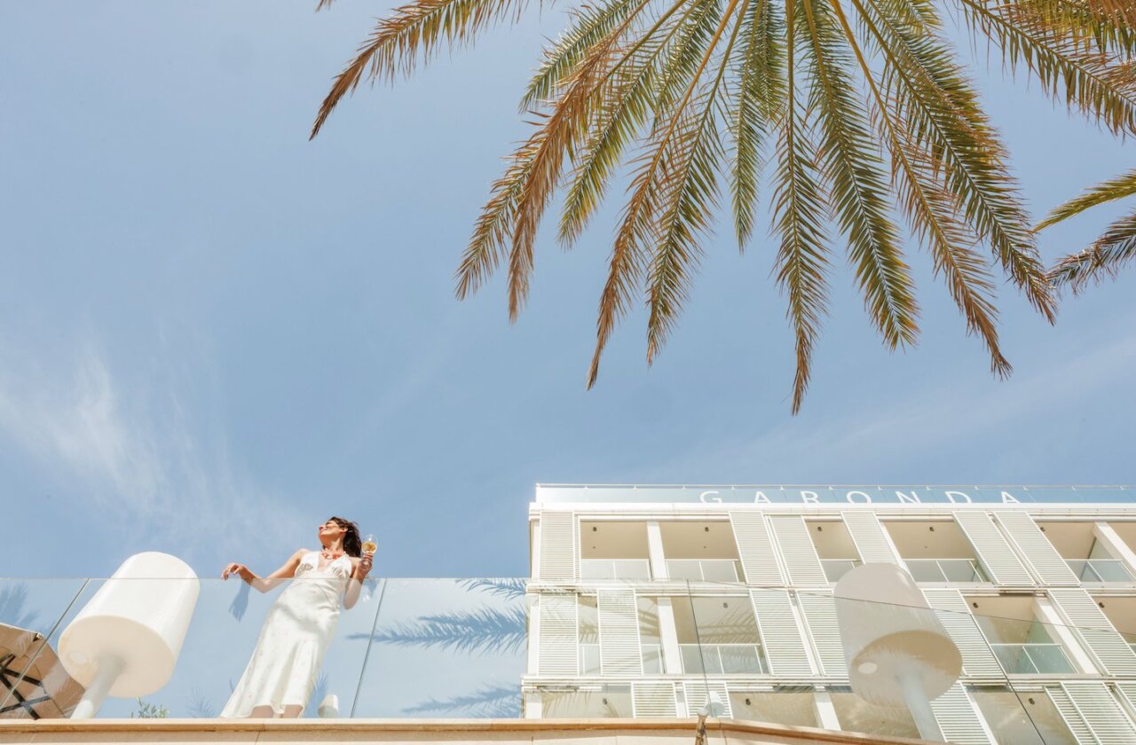Mujer con c&oacute;ctel en la terraza del hotel Garonda bajo palmeras