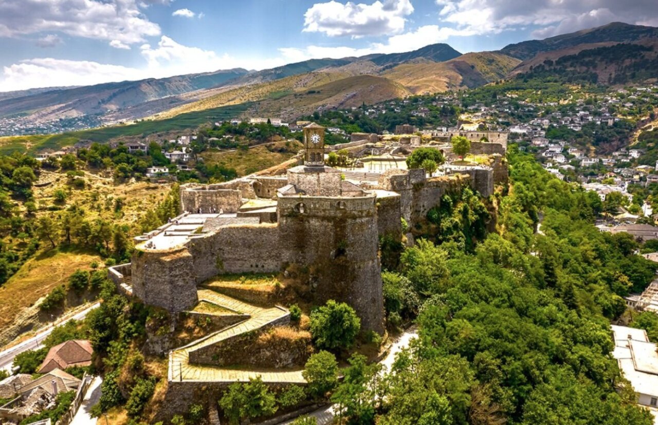 Vista panor&aacute;mica de un castillo en una monta&ntilde;a con un pueblo al fondo
