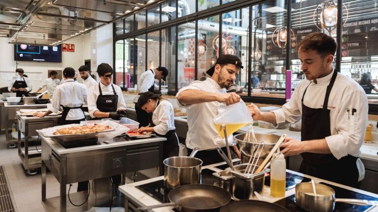 Estudiantes en un curso de hosteler&iacute;a cocinando en una cocina moderna