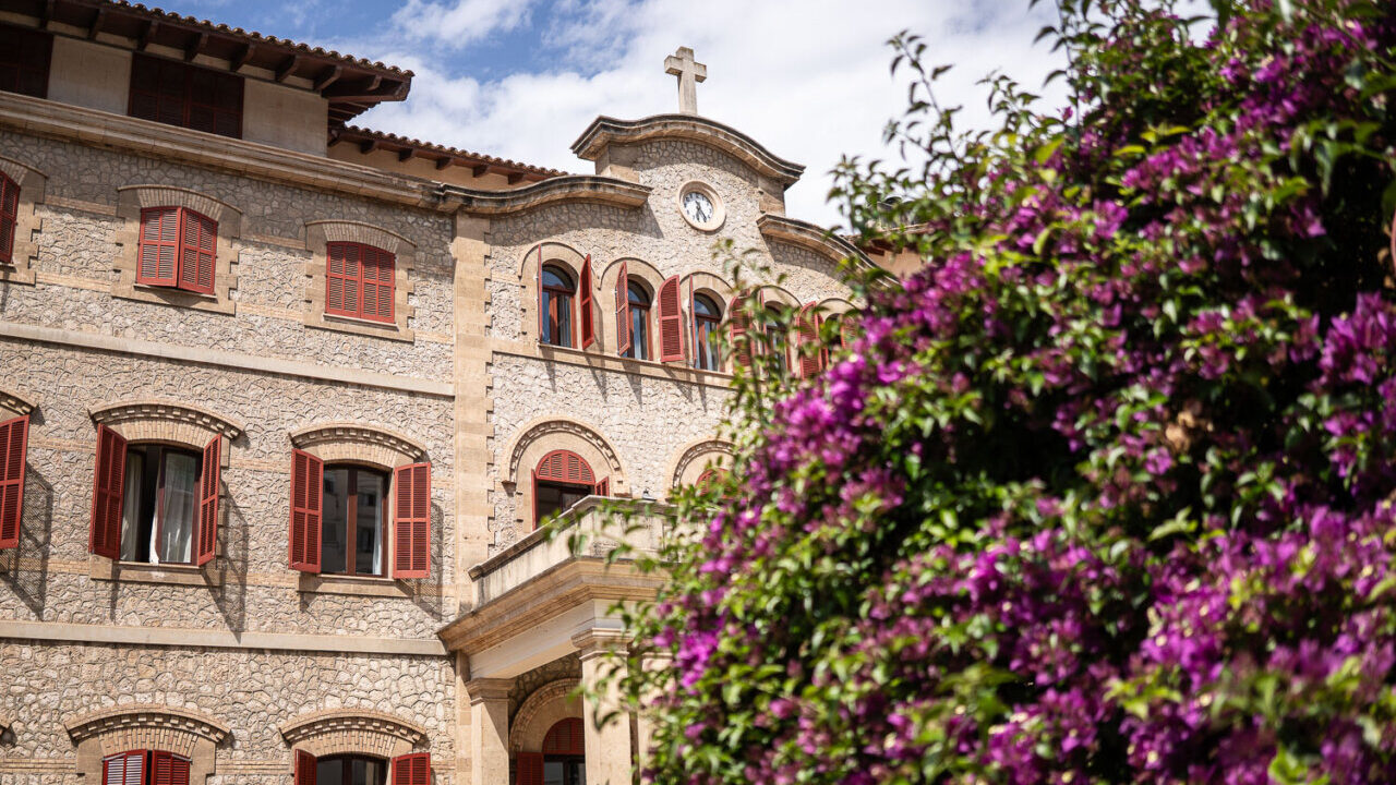 Vista del edificio de las Hermanitas de los Pobres en Palma con flores moradas