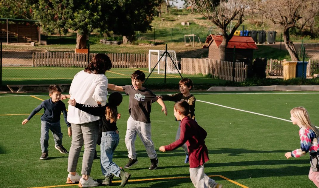 Ni&ntilde;os jugando en un campo de f&uacute;tbol con un adulto en Mallorca
