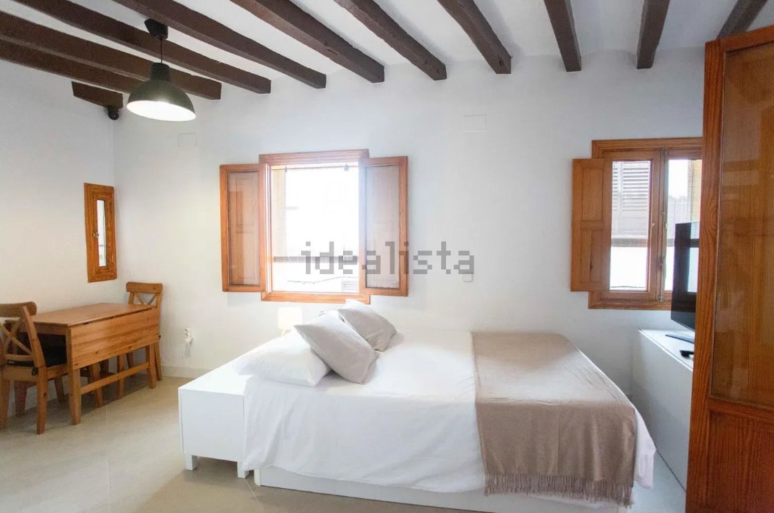 Interior de un estudio en alquiler en Palma con cama y mesa de trabajo