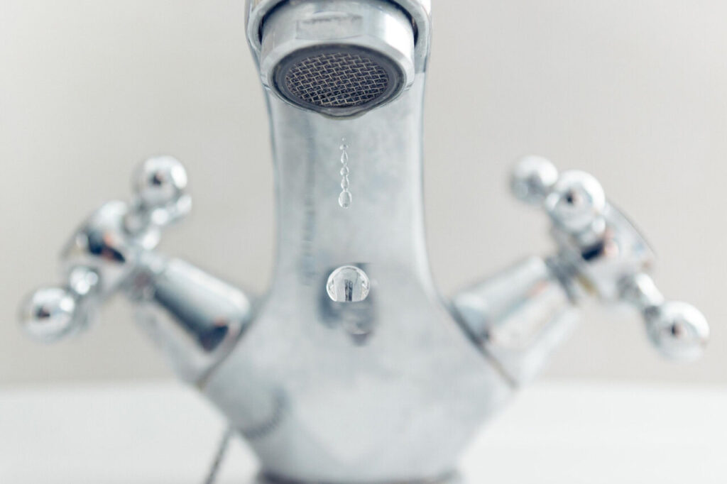Grifo de cocina goteando con agua en una gota