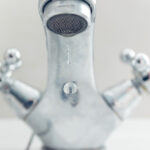 Grifo de cocina goteando con agua en una gota