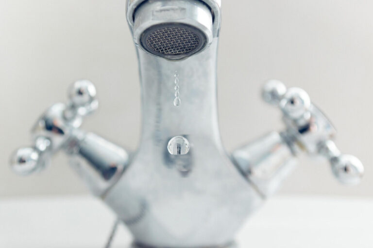 Grifo de cocina goteando con agua en una gota