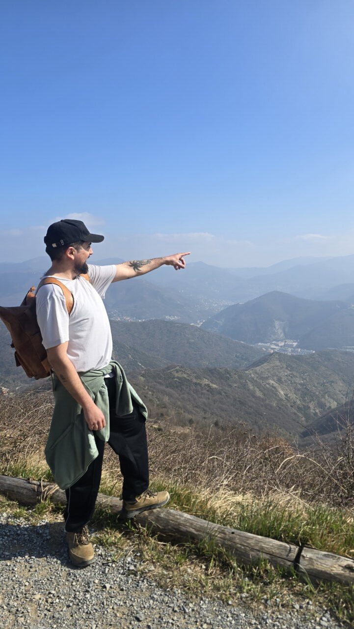 Hombre señalando un paisaje montañoso bajo un cielo despejado