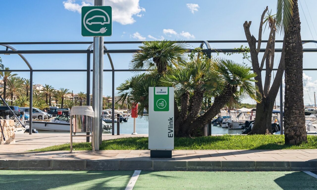 Punto de carga para veh&iacute;culos el&eacute;ctricos en un puerto con palmeras