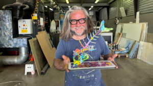 Lolo Garner sosteniendo una escultura colorida de sardina en su taller