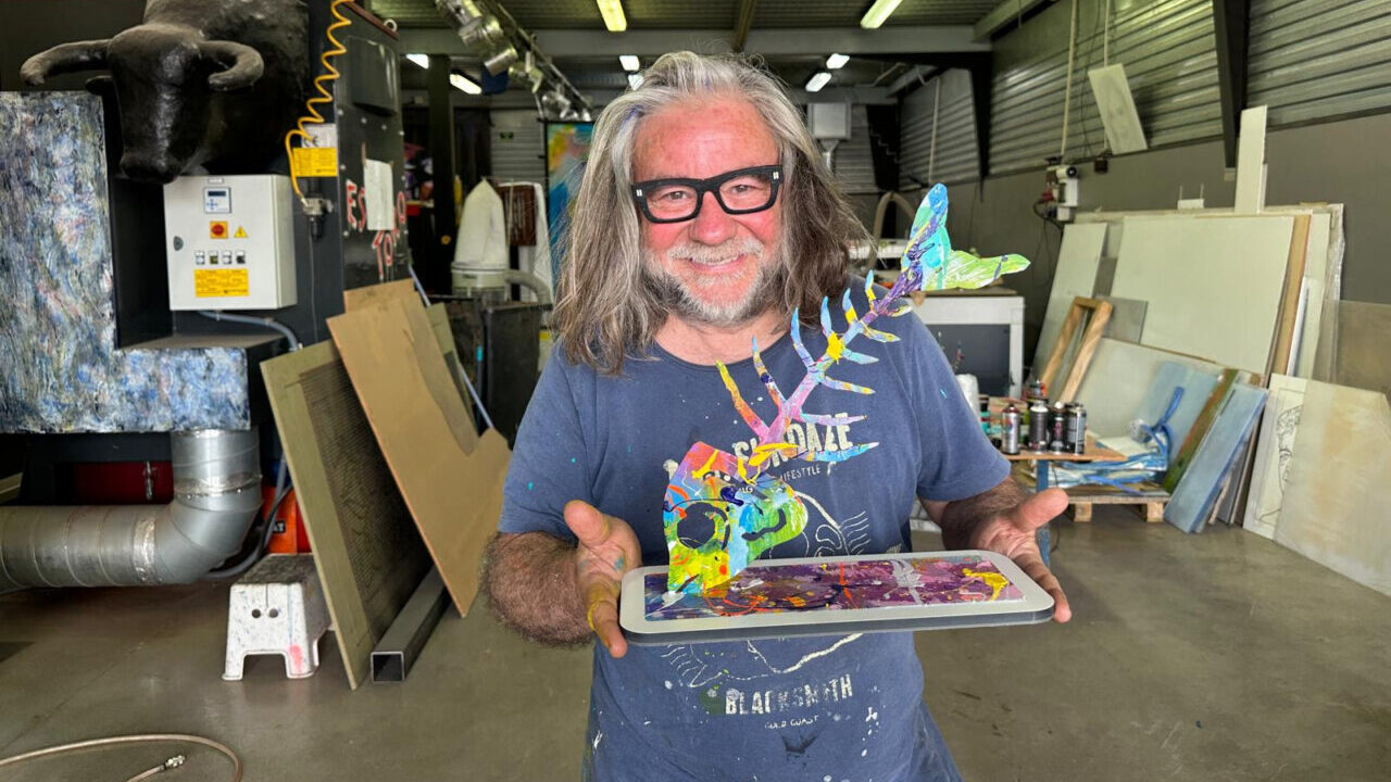 Lolo Garner sosteniendo una escultura colorida de sardina en su taller