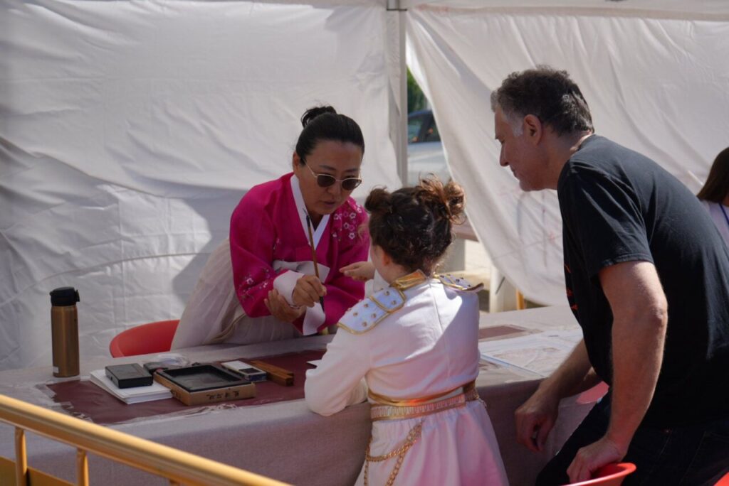 Persona en traje tradicional coreano interactuando con una ni&ntilde;a en evento friki