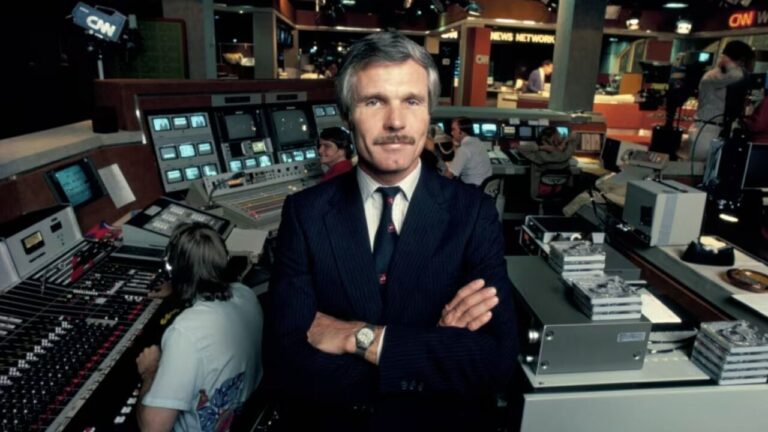 Ted Turner en el estudio de CNN con equipo de producci&oacute;n detr&aacute;s.