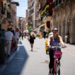Mujer montando una bicicleta rosa en una calle concurrida