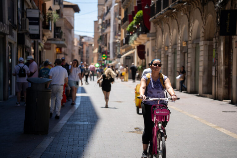Mujer montando una bicicleta rosa en una calle concurrida