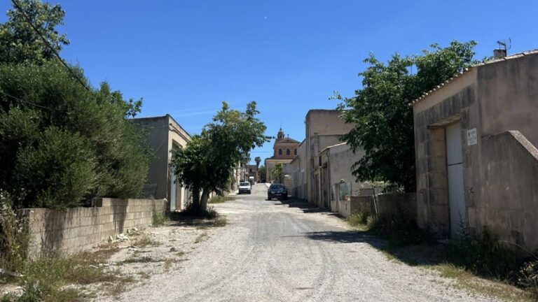 Vista de una calle en Cas Concos con edificios y &aacute;rboles