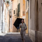 Mujer caminando por una calle estrecha con un paraguas en Mallorca