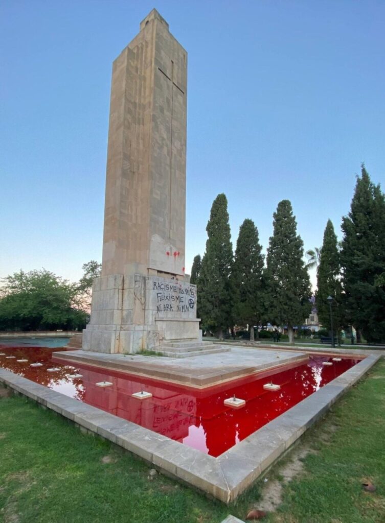 Monumento Sa Feixina con pintadas y agua roja alrededor