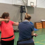 Dos mujeres practicando tiro con arco en un gimnasio