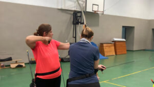 Dos mujeres practicando tiro con arco en un gimnasio
