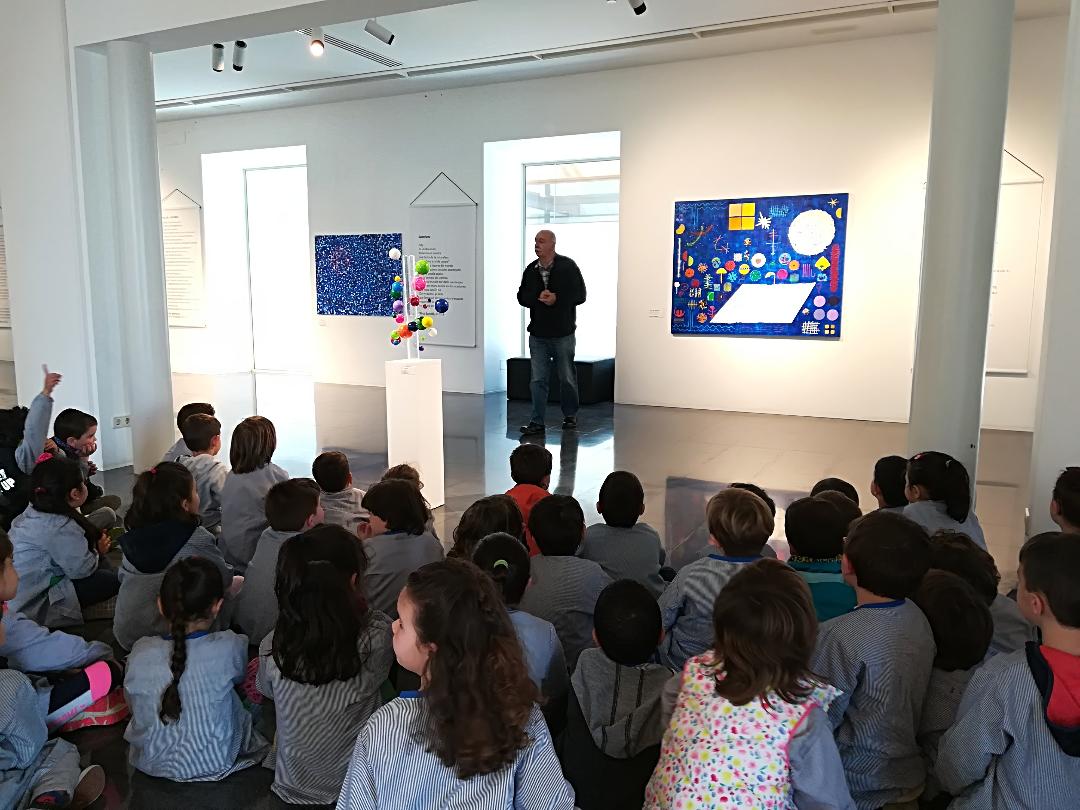 Niños sentados en el suelo durante una visita a una exposición de arte