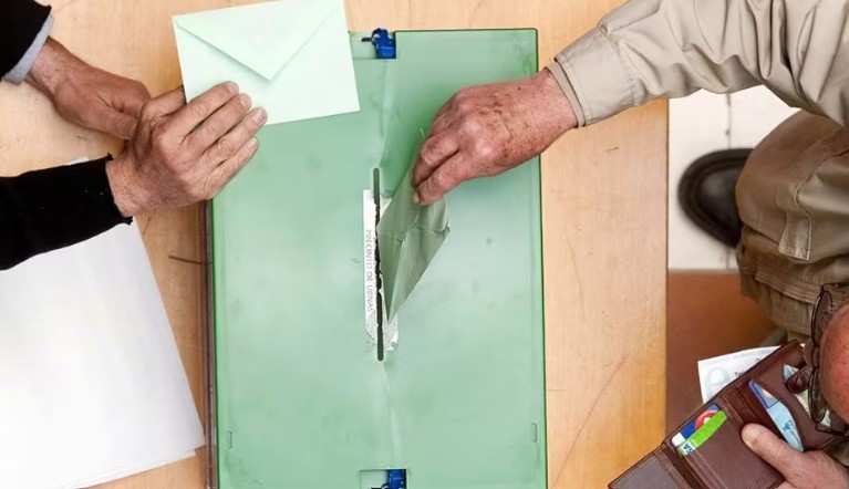 Personas votando en las elecciones andaluzas con sobres de votaci&oacute;n