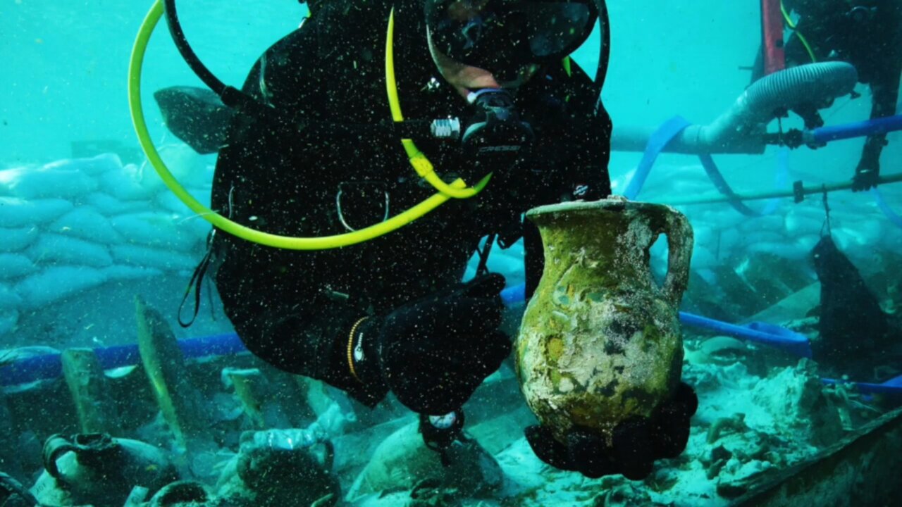 Investigador submarino sosteniendo una &aacute;nfora antigua en el pecio romano.