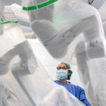 Médico observando un sistema de cirugía robótica en un quirófano moderno