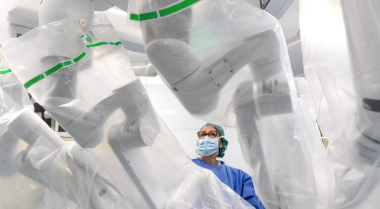 Médico observando un sistema de cirugía robótica en un quirófano moderno
