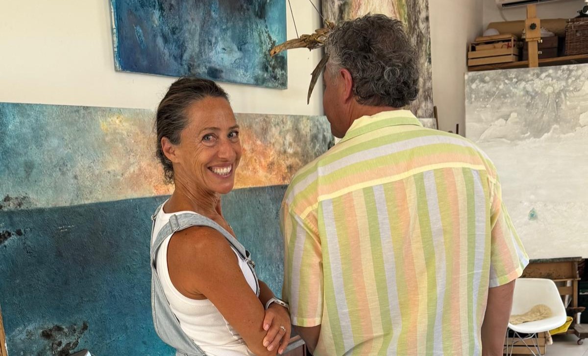 Carol Romero sonriendo en su estudio mientras conversa con un hombre