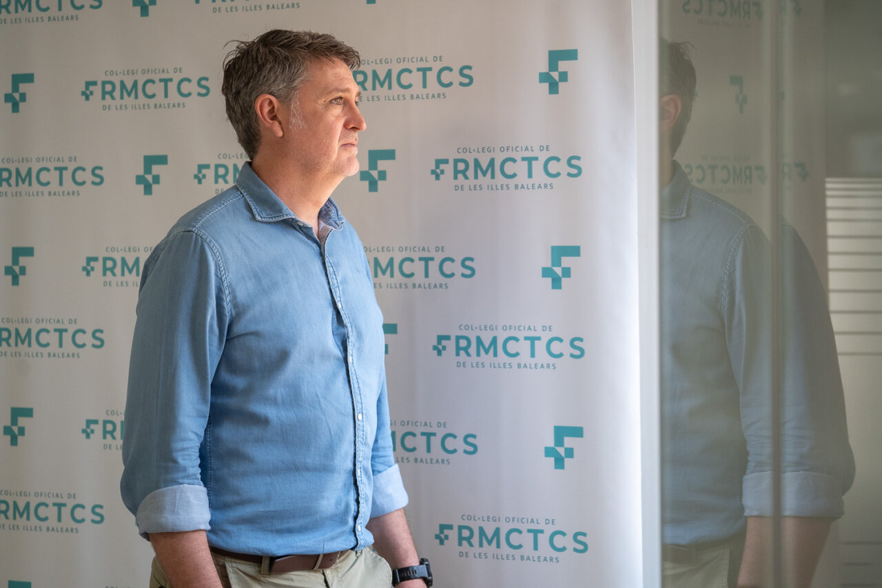 Hombre de perfil frente a un fondo con el logo del Colegio Oficial de Farmac&eacute;uticos