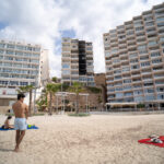 Vista de un edificio dañado por incendio en Magaluf con personas en la playa