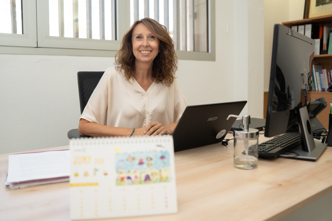 Mujer sonriente en un escritorio con computadora y calendario