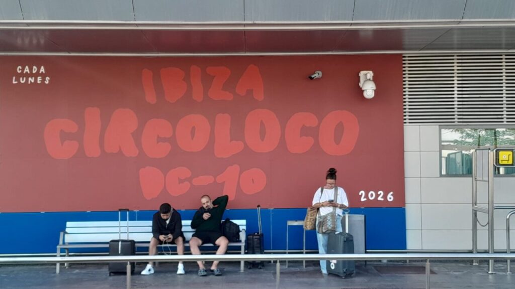 Mural de Circoloco en el aeropuerto de Ibiza con personas esperando.