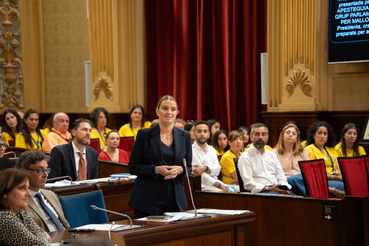 Mujer hablando en el Parlamento con público atento en el fondo