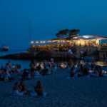 Vista nocturna de la playa Camp de Mar con un restaurante iluminado
