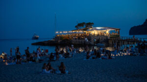 Vista nocturna de la playa Camp de Mar con un restaurante iluminado