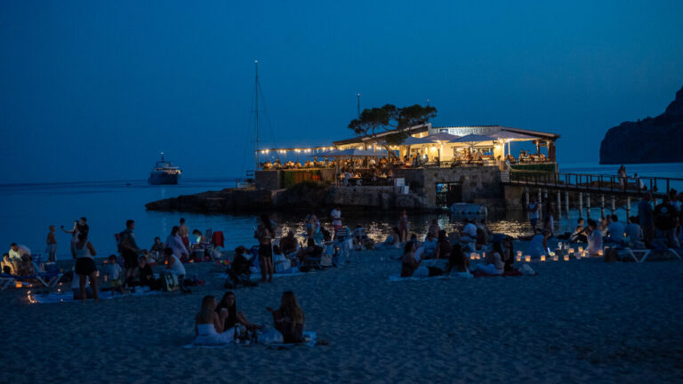 Vista nocturna de la playa Camp de Mar con un restaurante iluminado