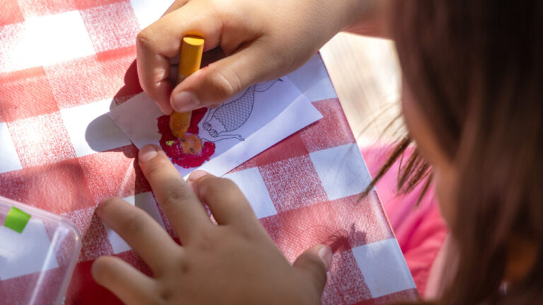 Ni&ntilde;a coloreando en una mesa de actividades de verano