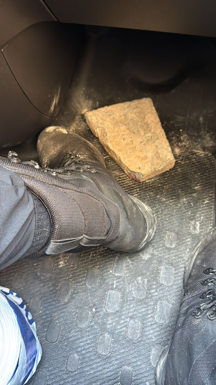 Botas de policía junto a un adoquín en el vehículo policial