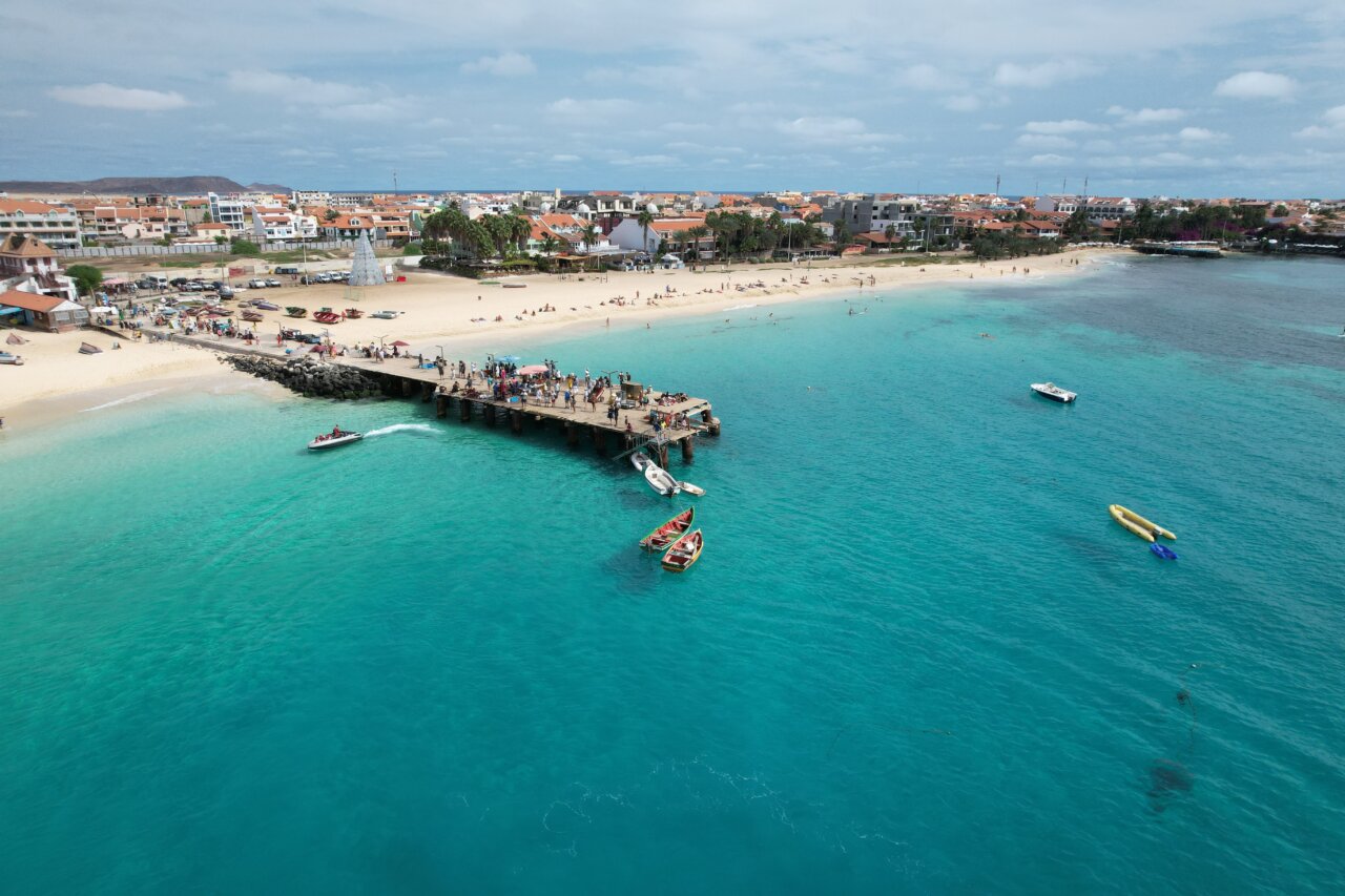 Vista aérea de la playa y puerto en Cabo Verde con barcos y turistas.