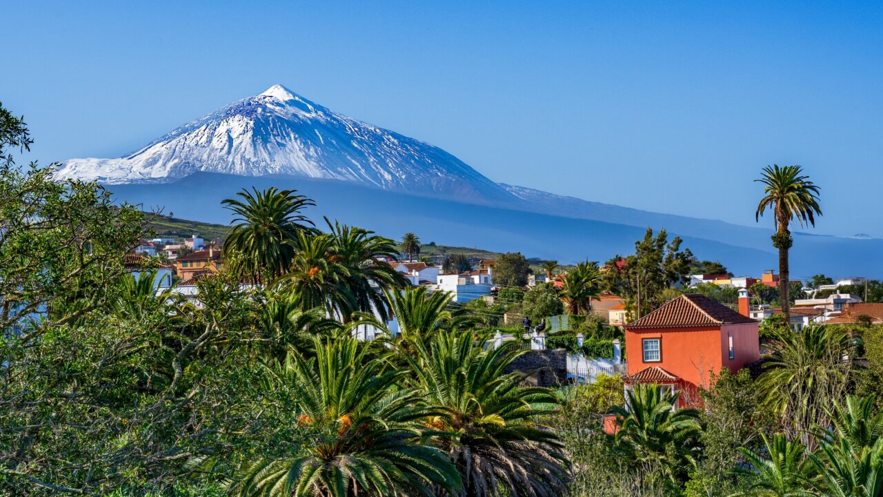 Vista del Teide en Tenerife con palmeras y casas coloridas