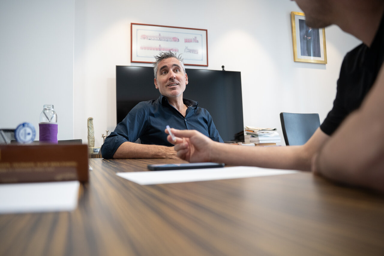 Hombre conversando en una reuni&oacute;n en una oficina moderna