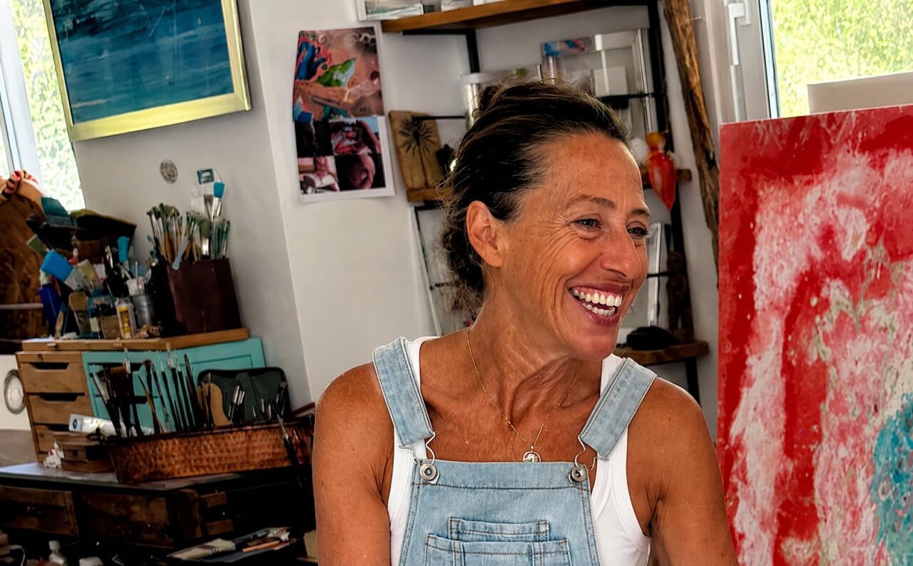 Carol Romero sonriendo en su estudio de arte durante una entrevista