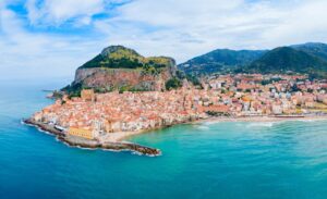 Vista panor&aacute;mica de un pueblo costero en Sicilia con monta&ntilde;as al fondo