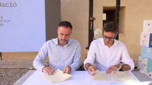 Dos hombres firmando documentos en un evento sobre viviendas en ParcBit