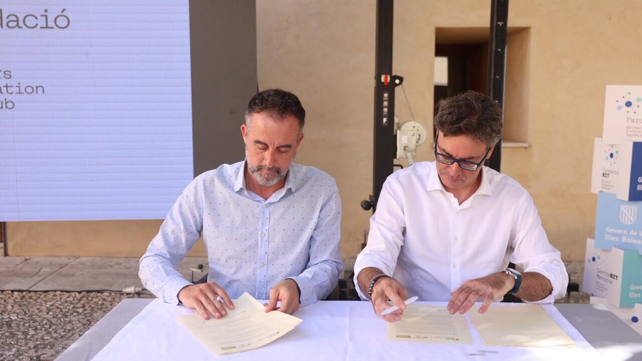 Dos hombres firmando documentos en un evento sobre viviendas en ParcBit