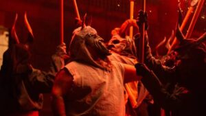 Grupo de personas con m&aacute;scaras y antorchas en un correfoc en Palma.