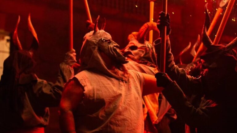 Grupo de personas con máscaras y antorchas en un correfoc en Palma.