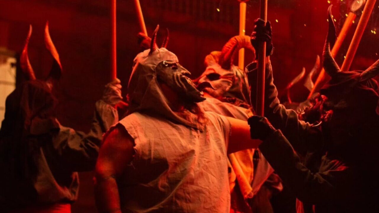 Grupo de personas con m&aacute;scaras y antorchas en un correfoc en Palma.