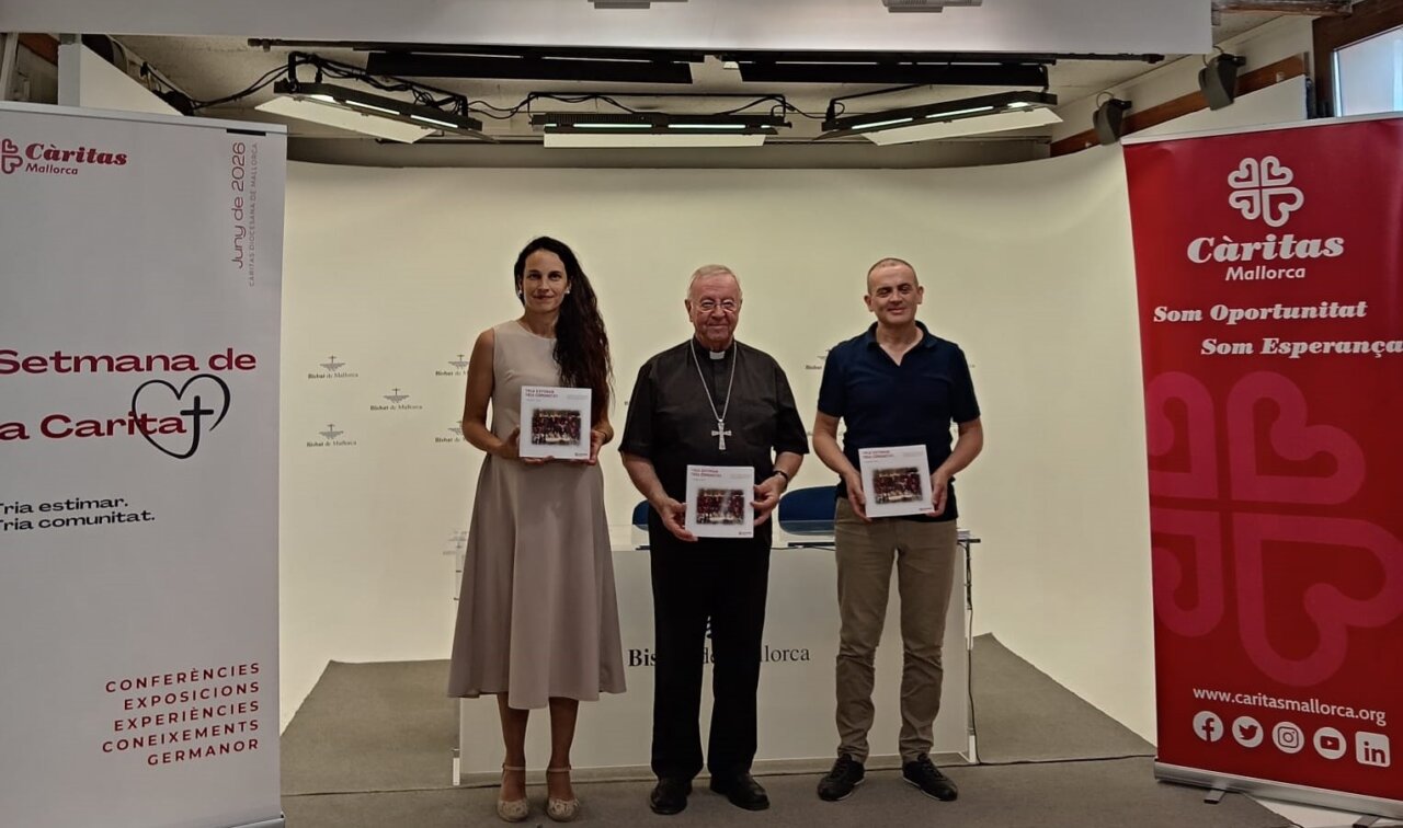 Presentaci&oacute;n de la memoria de C&aacute;ritas Mallorca con tres personas sosteniendo libros